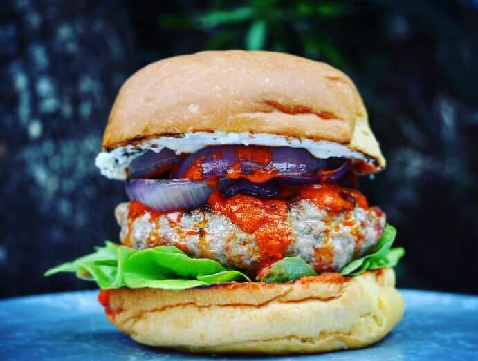 Lamb burger, harissa & onions Lamb burger with harissa, red onion and lettuce on a plate