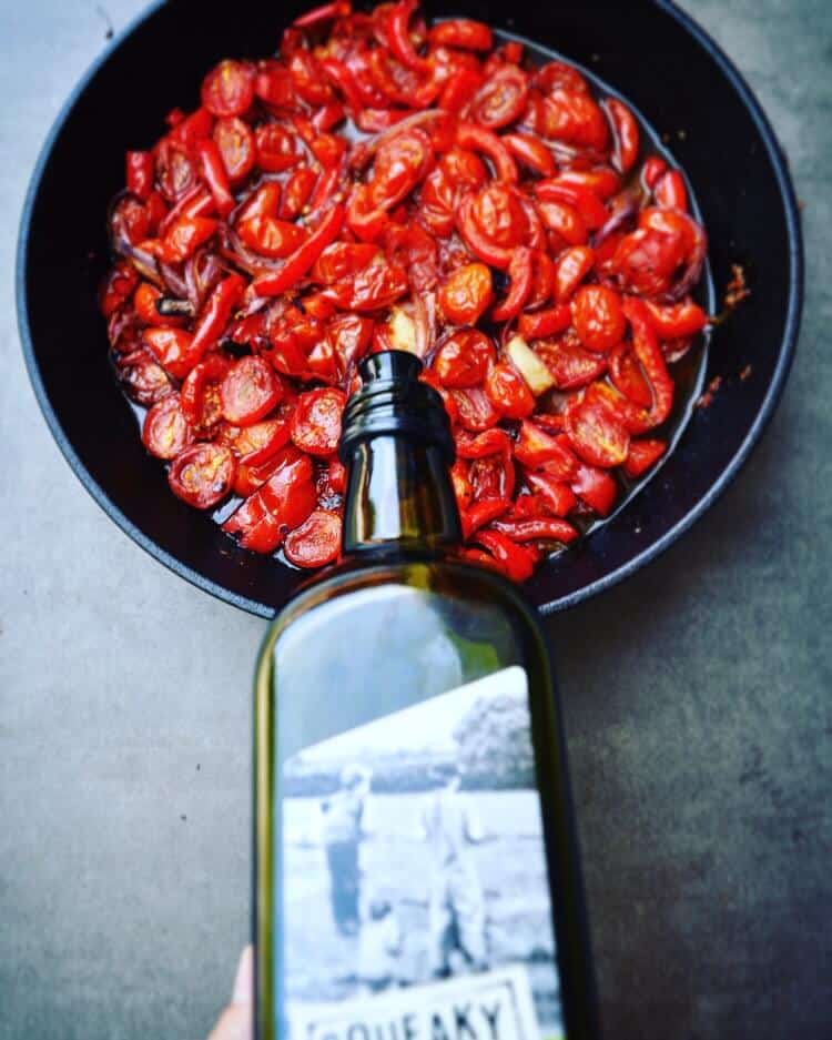 Squeaky gate olive oil being poured into a dish of tomatoes