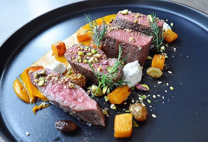 Lamb & Pistachio Dukkah lamb loin on a plate with vegetables and pistachio dukkah