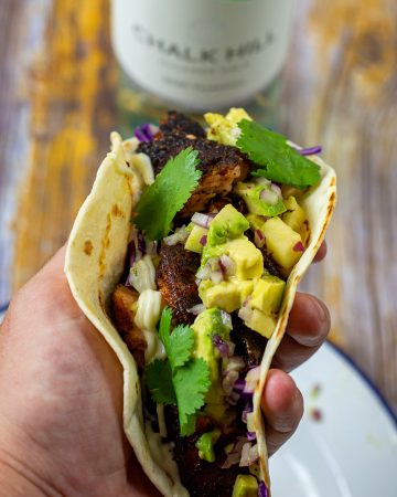 someone holding a blackened salmon taco