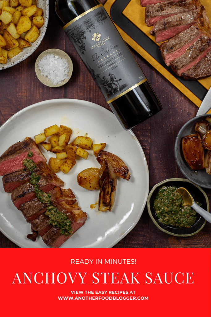 Cooked steak topped with anchovy steak sauce & potatoes on a plate. Barossa shiraz beside it