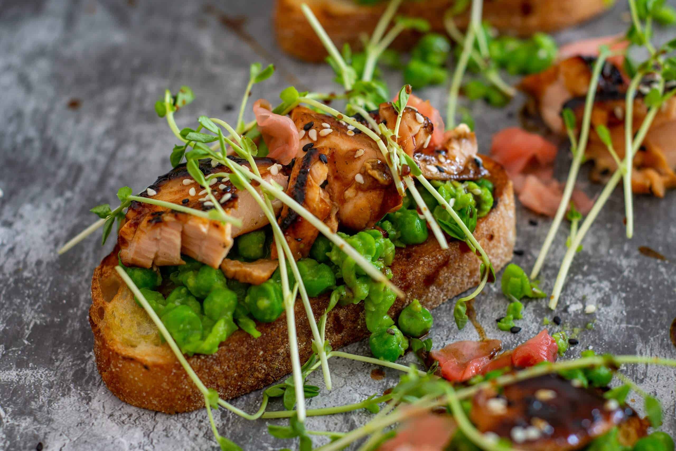 pan-fried salmon teriyaki on toast with crushed peas, pea shoots and pickled ginger