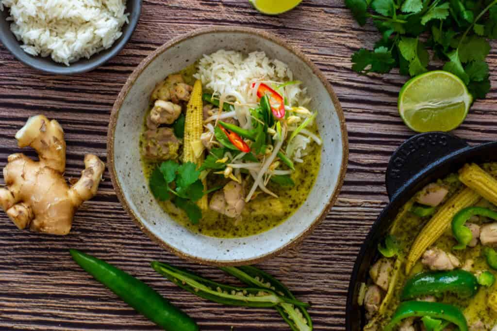 thai green curry in a bowl, coriander, ginger & rice on table