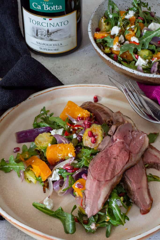 grilled lamb salad, a bowl of roasted veg salad and a bottle of red wine