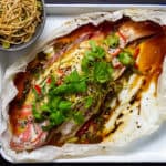 Cooked fish en papillote with bowl of noodles