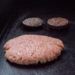Pork burger and black pudding cooking on a flat top