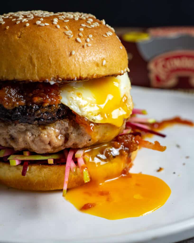 Close up of pork & black pudding burger with runny egg yolk. Clonakilty black pudding packet in background