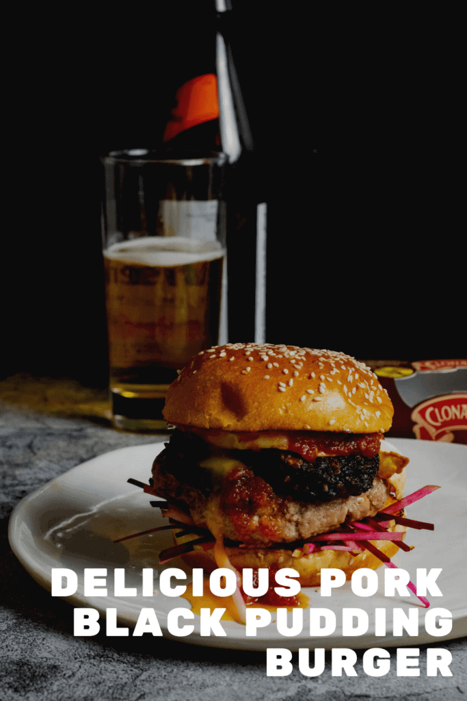 Pork & black pudding burger on a white plate with a beer in background