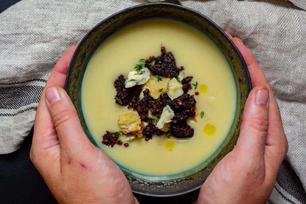 Hands holding a bowl of potato & leek soup