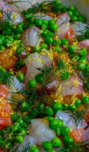 Raw fish, peas & dill in a pan for fish pie