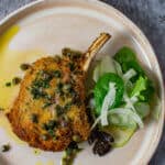cooked veal cutlet, salad & sauce on a plate