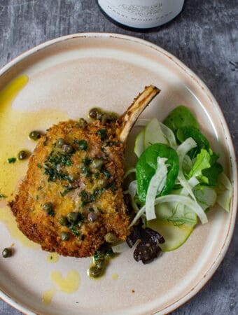 cooked veal cutlet, salad & sauce on a plate