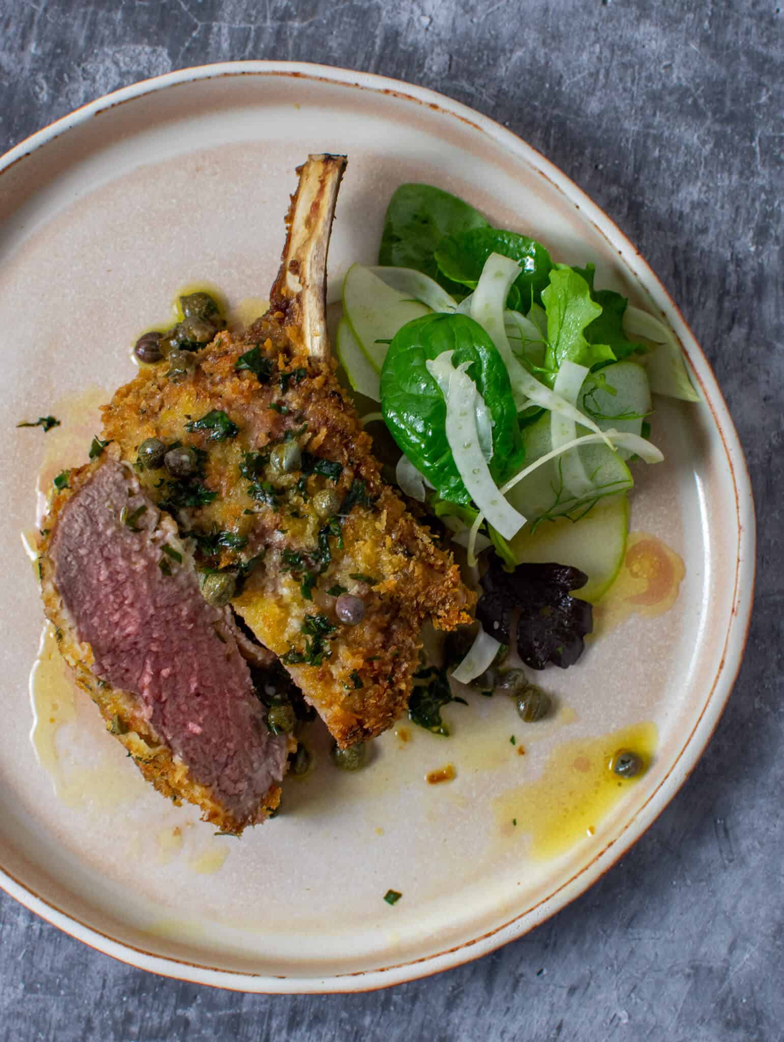 crumbed veal cutlet sliced in half with lemon caper sauce and salad