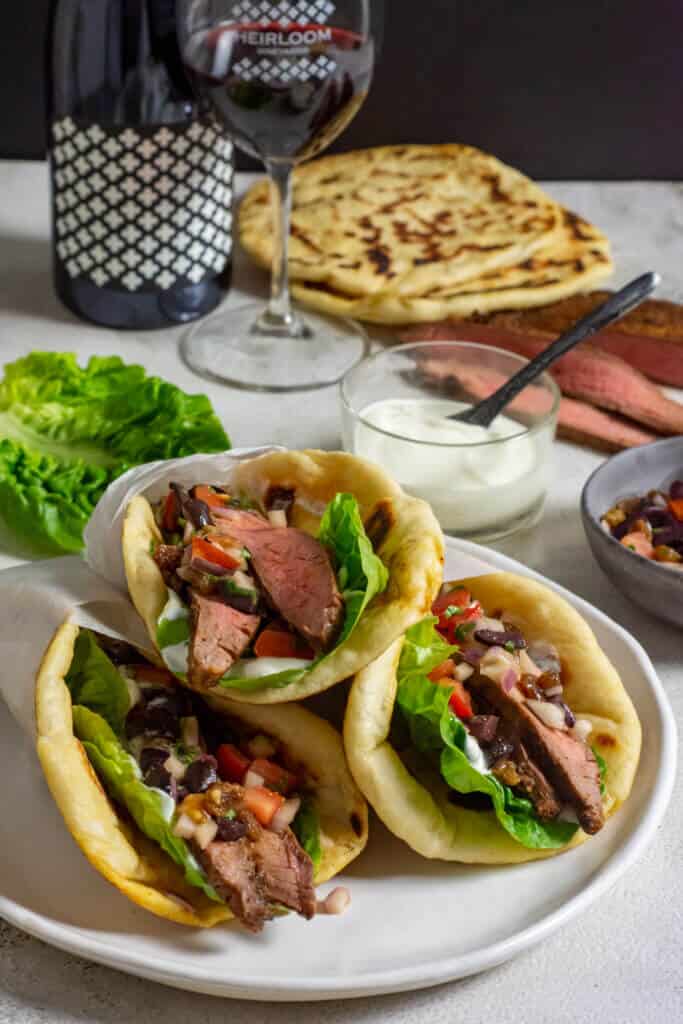 red wine, morrocan steak pitas, yoghurt & steak on a table