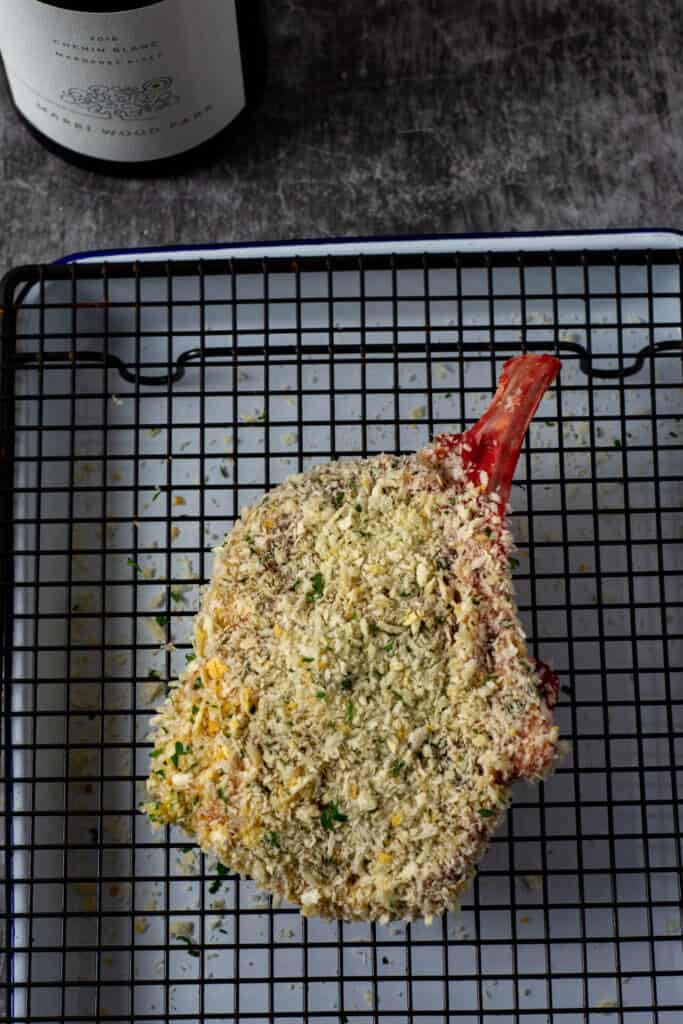 raw crumbed veal cutlet on wire rack on tray