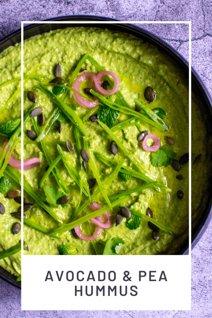 black bowl with avocado & pea hummus topped with pickled onions, pepitas, herbs & snowpeas