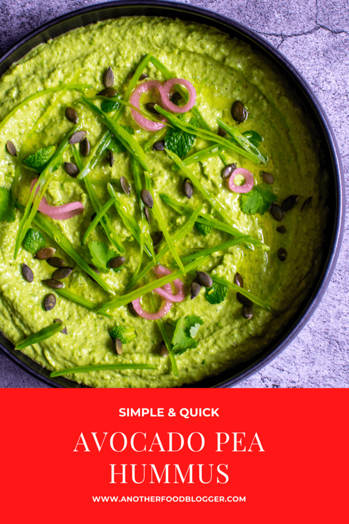 black bowl with avocado & pea hummus topped with pickled onions, pepitas, herbs & snowpeas