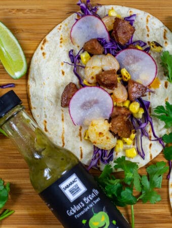 chorizo & prawn tacos on chopping board with sabarac hot sauce