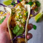 someone holding a crispy fish taco