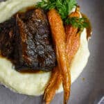mushroom braised short ribs, cauliflower puree & carrots in a bowl on wooden table