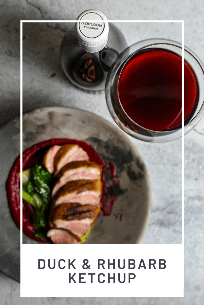 Duck breast, rhubarb ketchup & asian greens in a made of australia bowl on a table with heirloom pinot noir