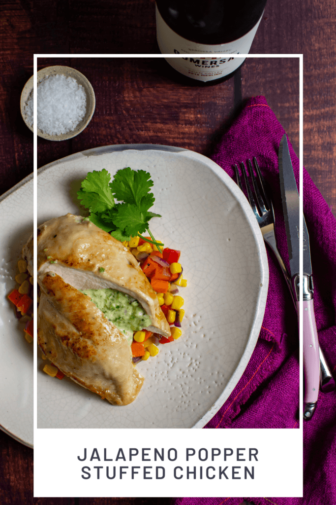 jalapeno popper stuffed chicken & corn hash on a plate, pink napkin, laguiole steak knife and bottle of gomersal wine