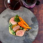 pork tenderloin, creamed spianch & carrots on a made of australia plate with a btl of mazzini pinot noir