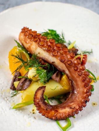 Grilled octopus salad on a white plate