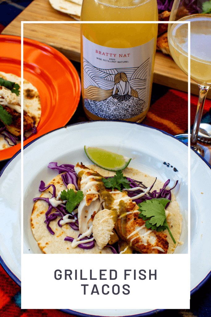 grilled fsh taco on a white plate with wine glass and bottle of marri wood park pet nat behind it