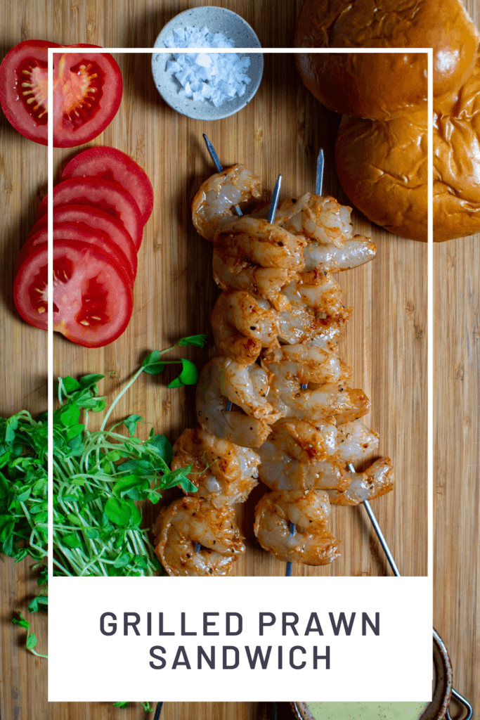 marinated prawn skewers, tomatoes. peashoots & brioche buns on a chopping board