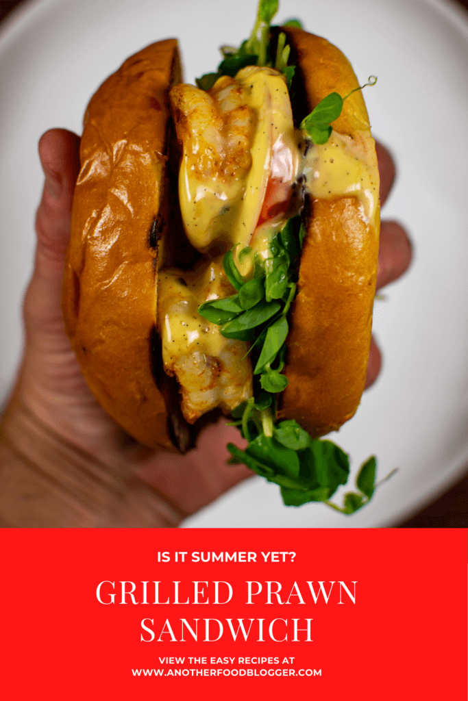 someone holding a grilled prawn sandwich above a white plate