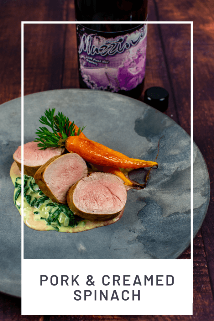 pork tenderloin, creamed spianch & carrots on a made of australia plate with a btl of mazzini pinot noir