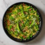 pea & baco risotto in a black bowl