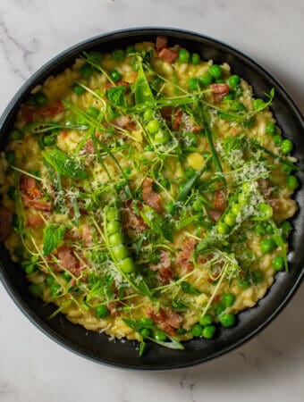 pea & baco risotto in a black bowl