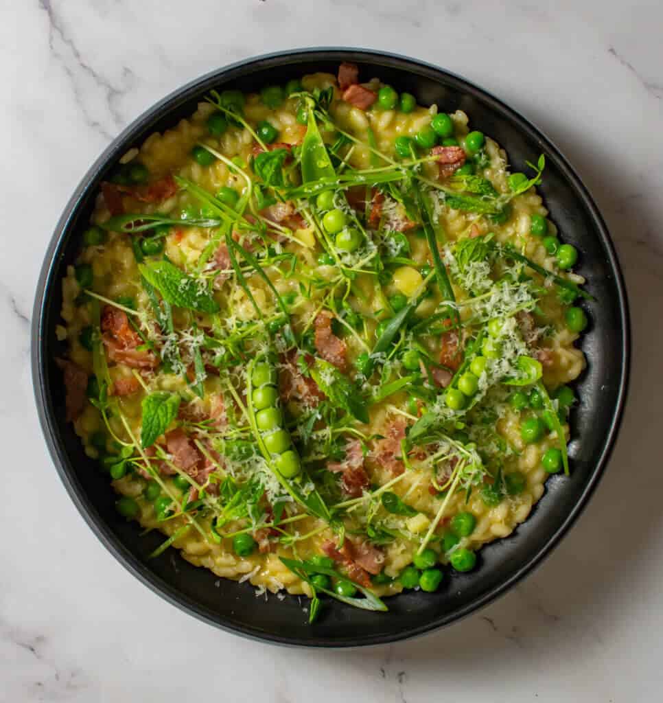 pea & baco risotto in a black bowl