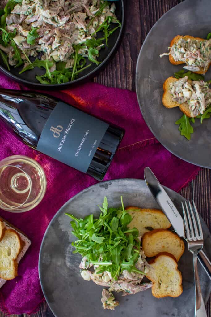 birds eye view of braised ham hock salad on made of australia plates, jackson brooke chardonnay on a wooden table