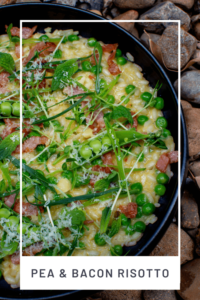 pea & bacon risotto in a black bowl on top of loads of stones