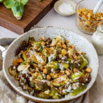 charred brussel sprouts & pangrattato in a bowl with a chopping board, brussel sprouts in the background