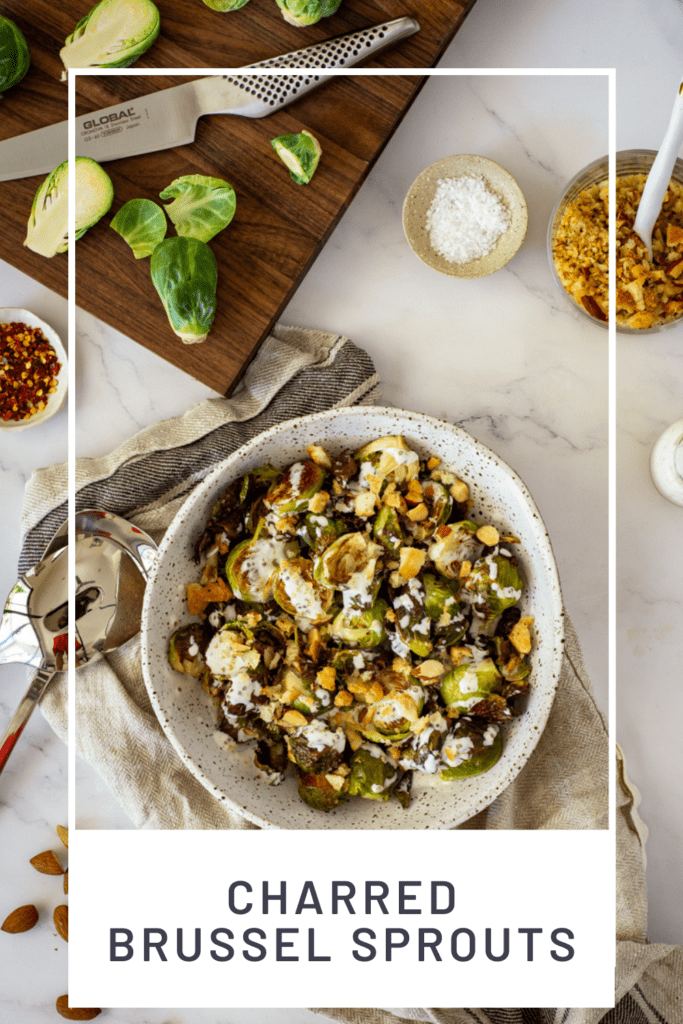 charred brussel sprouts & pangrattato in a bowl with a chopping board, brussel sprouts in the background