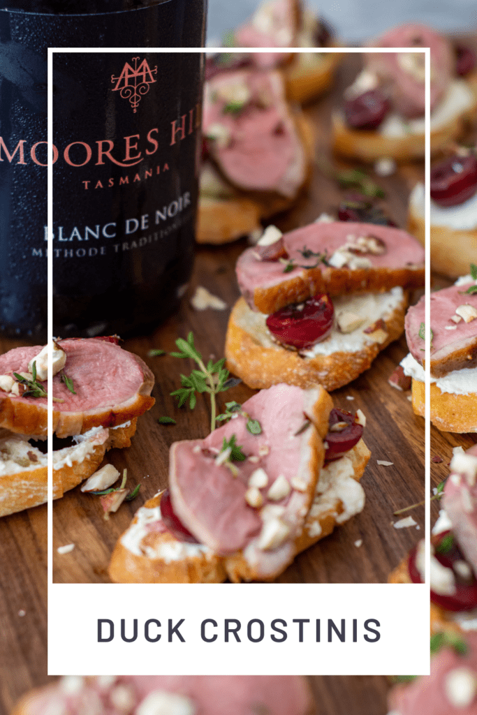 duck crostinis with cherries & goat cheese on wooden chopping board & moores hill blanc de noir