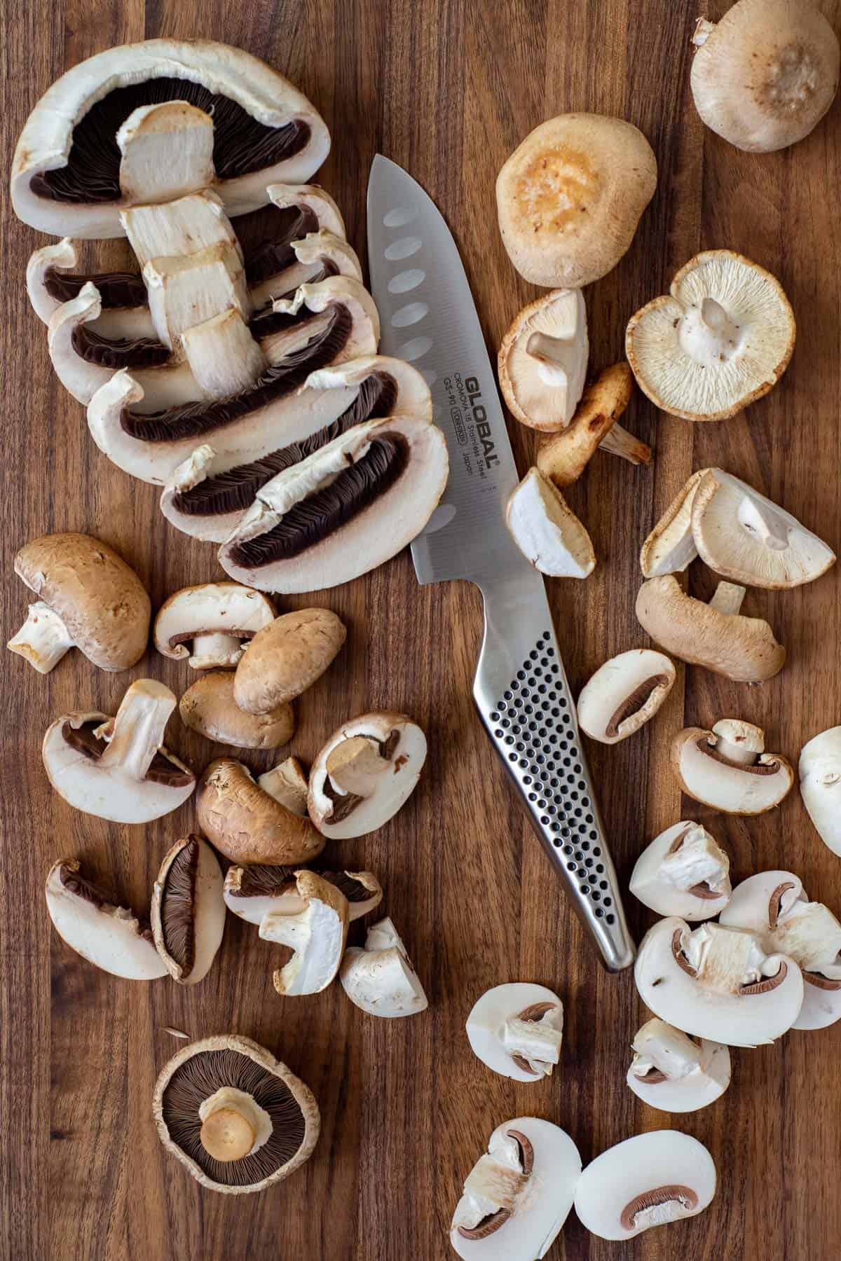 mixed mushrooms on a global chopping board with a global knife