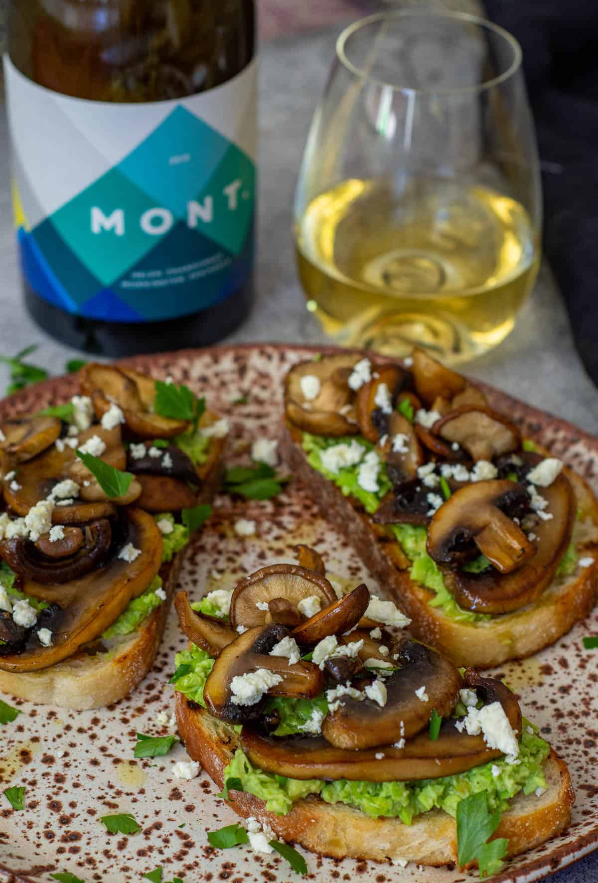 mushroom avocado toast on a plate with Mont chardonnay in background