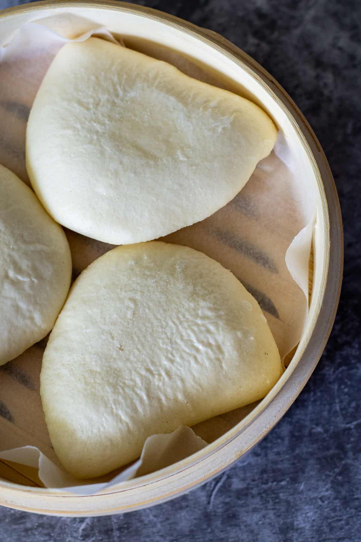 uncooked bao in a bamboo steamer