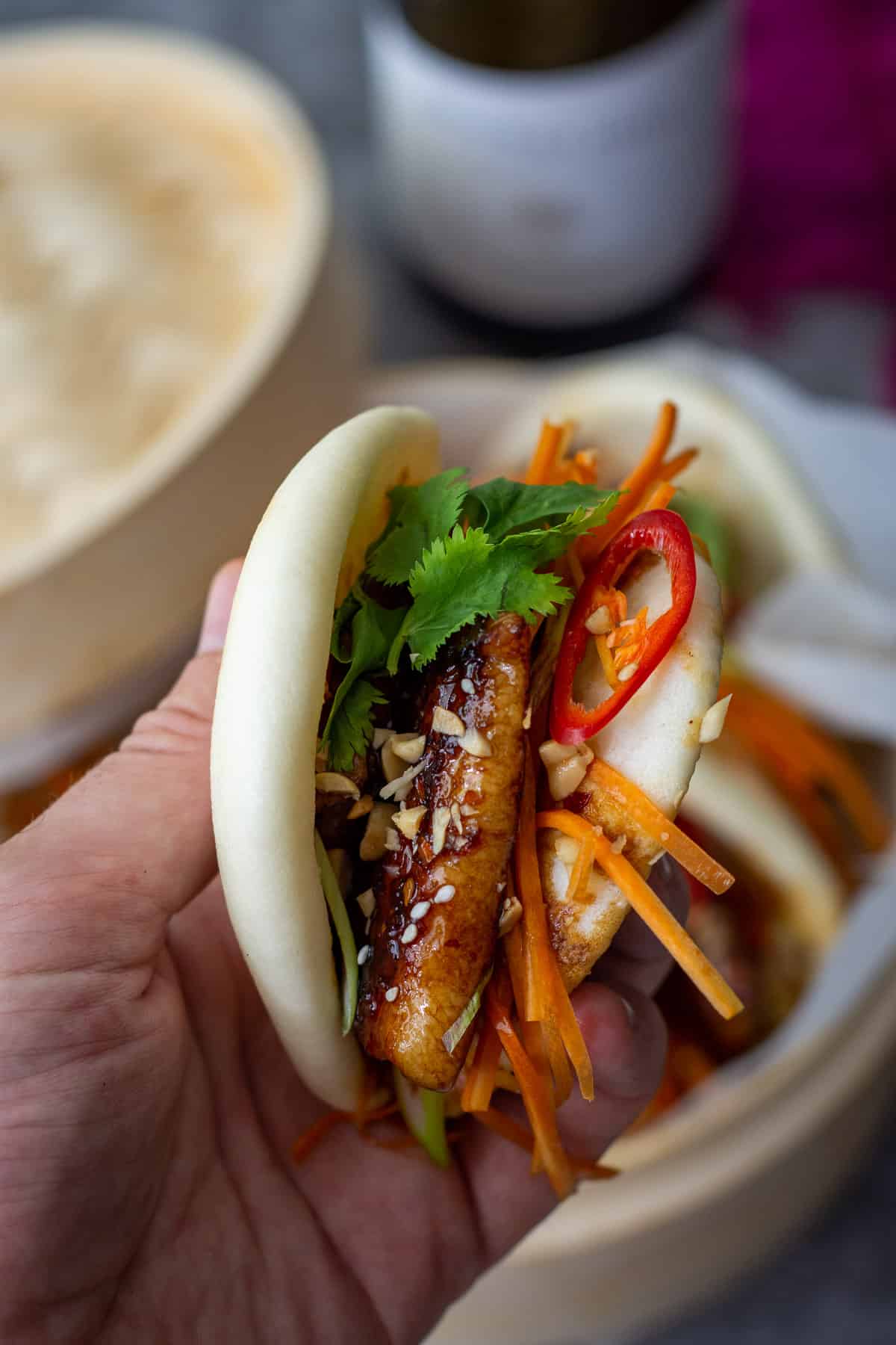 someone holding a pork belly bao