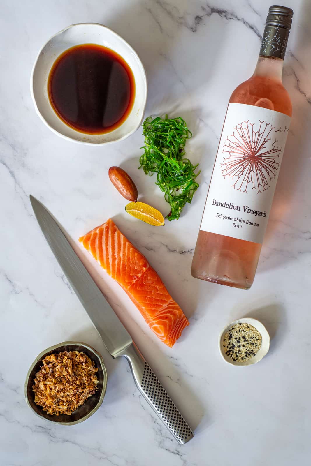 Dandelion rose, ponzu sauce, raw salmon & a global knife on a counter top