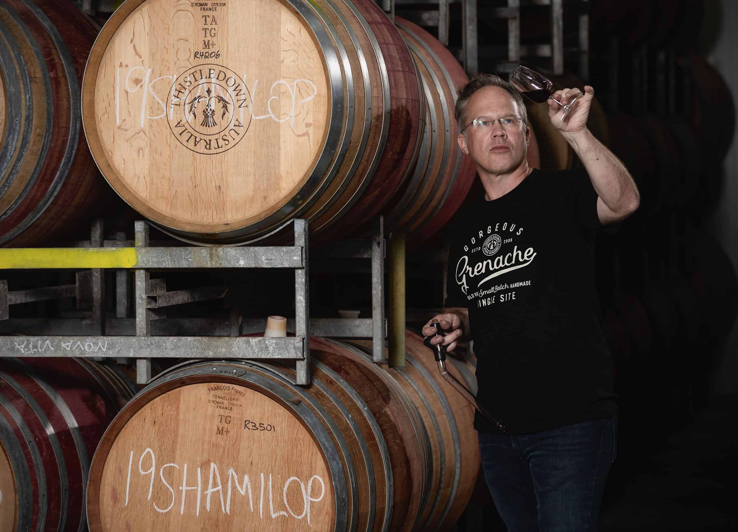 Giles inspecting wine beside wine barrels