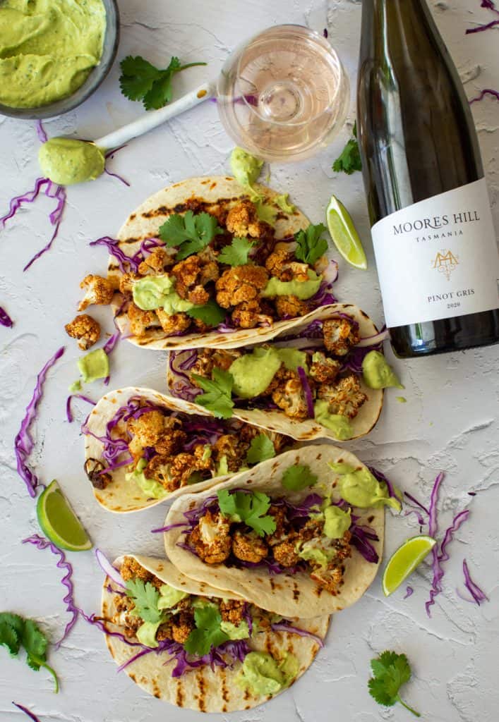 birds eye view of roasted cauliflower taocs and a bottle of moores hill pinot gris next to them
