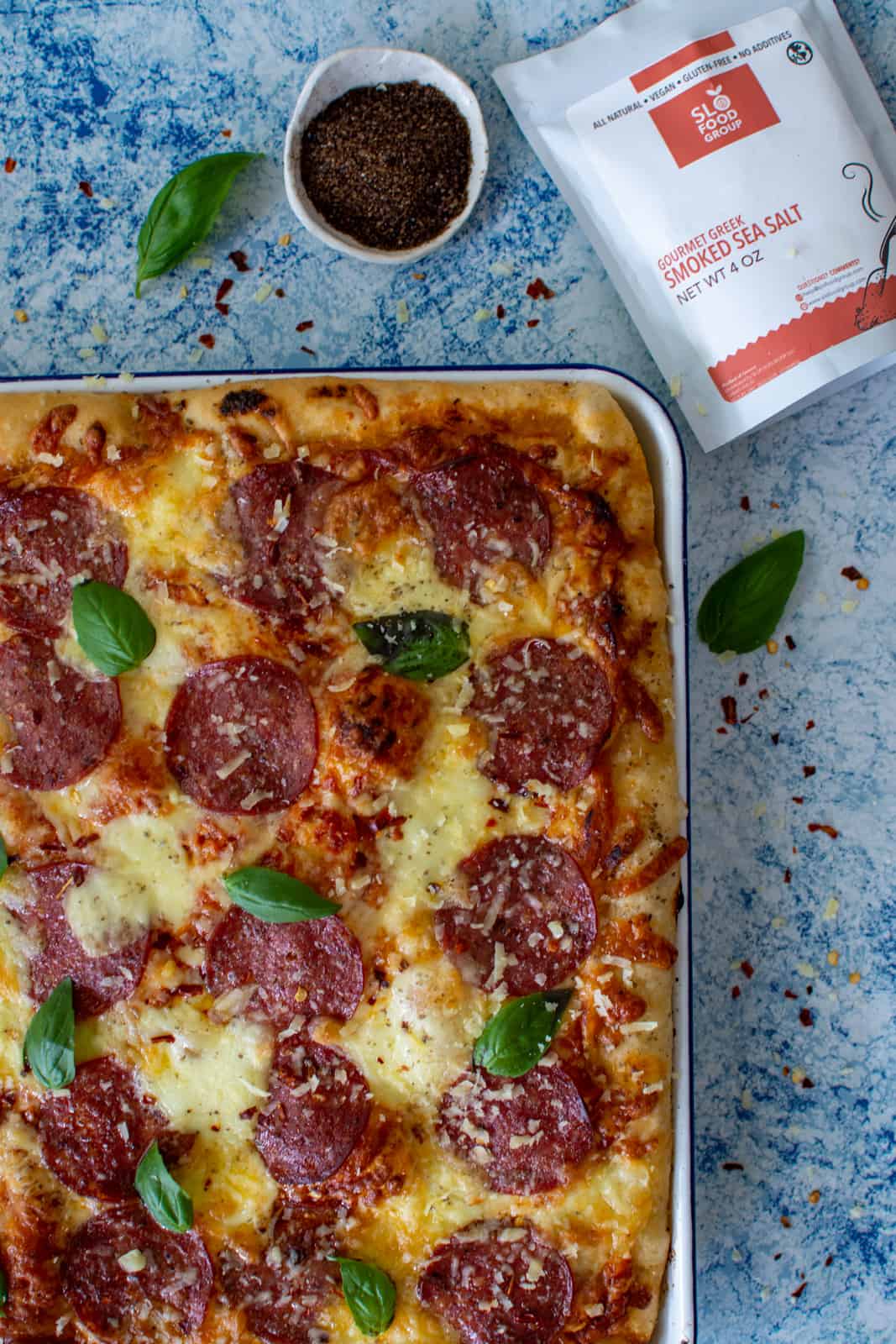 Focaccia pizza aka sheet pan pizza with slofoodgroup smoked salt next to it