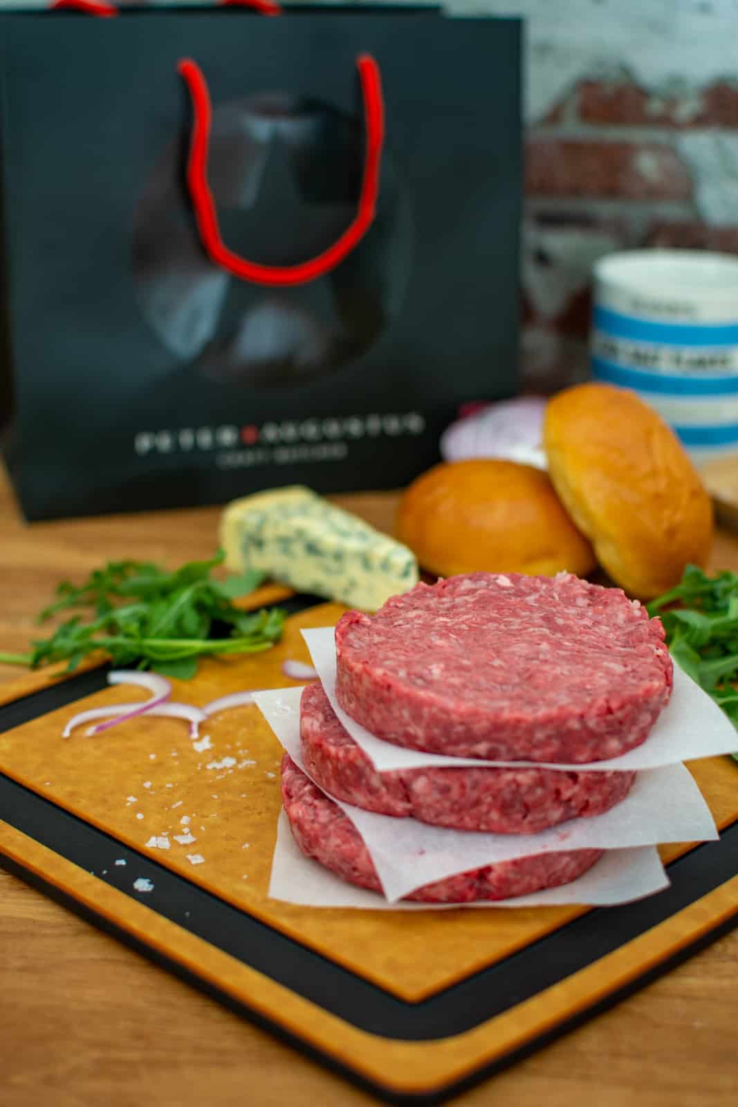 wagyu burger patties on a chopping board with rocket, onion, blue cheese & burger buns