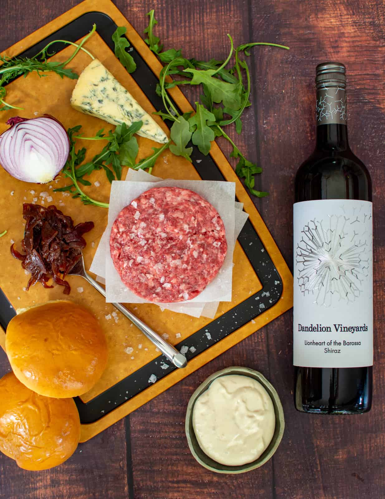 wagyu burger patties on chopping board with caramelised onions, blue cheese and Dandelion shiraz